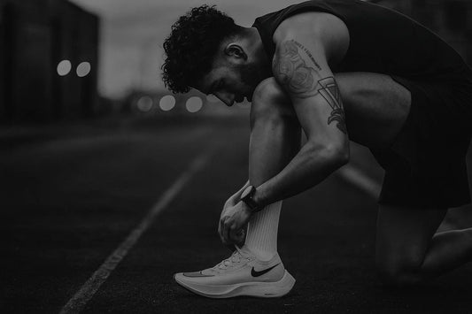 Focused runner tying laces before starting a long cardio session at dawn.